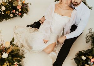 Romantic couple posing among floral decorations in formal attire.