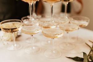 Multiple champagne coupes arranged on white surface with delicate lighting.