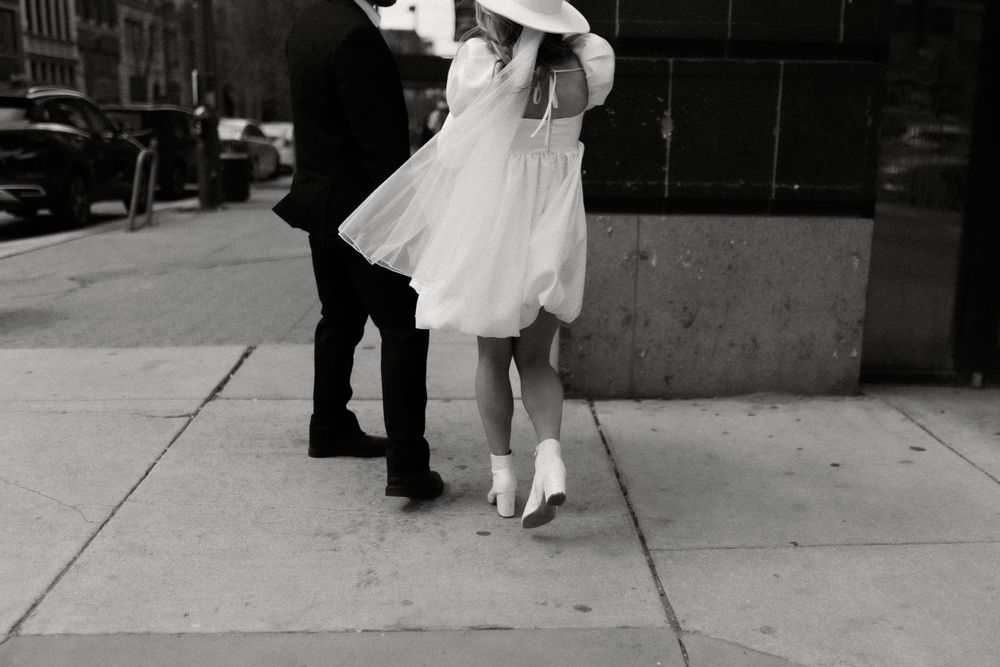 Black and white photo of a couple's feet in formal attire dancing on a city sidewalk.