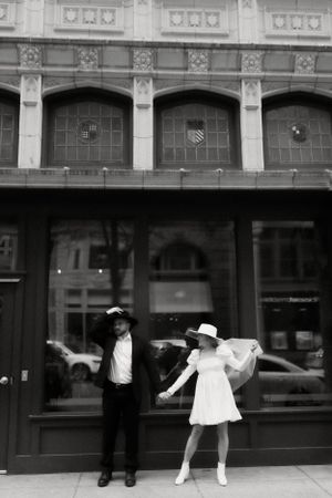 Vintage-style black and white portrait in front of an ornate building facade.