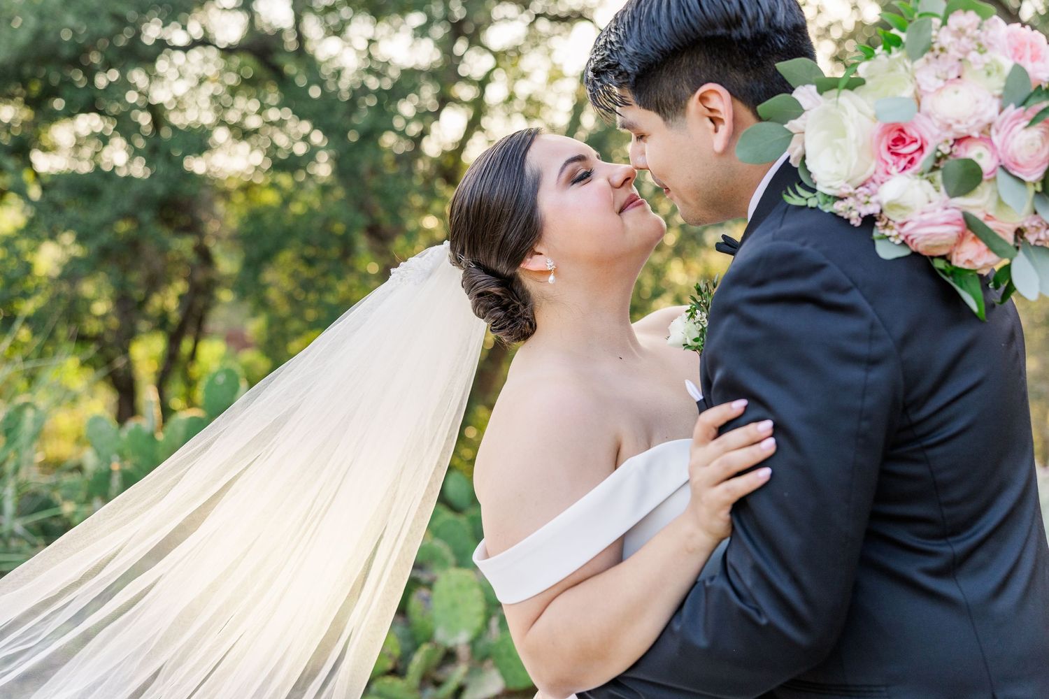 Joyful wedding party poses outdoors with bridesmaids in blush dresses and groomsmen in navy suits.