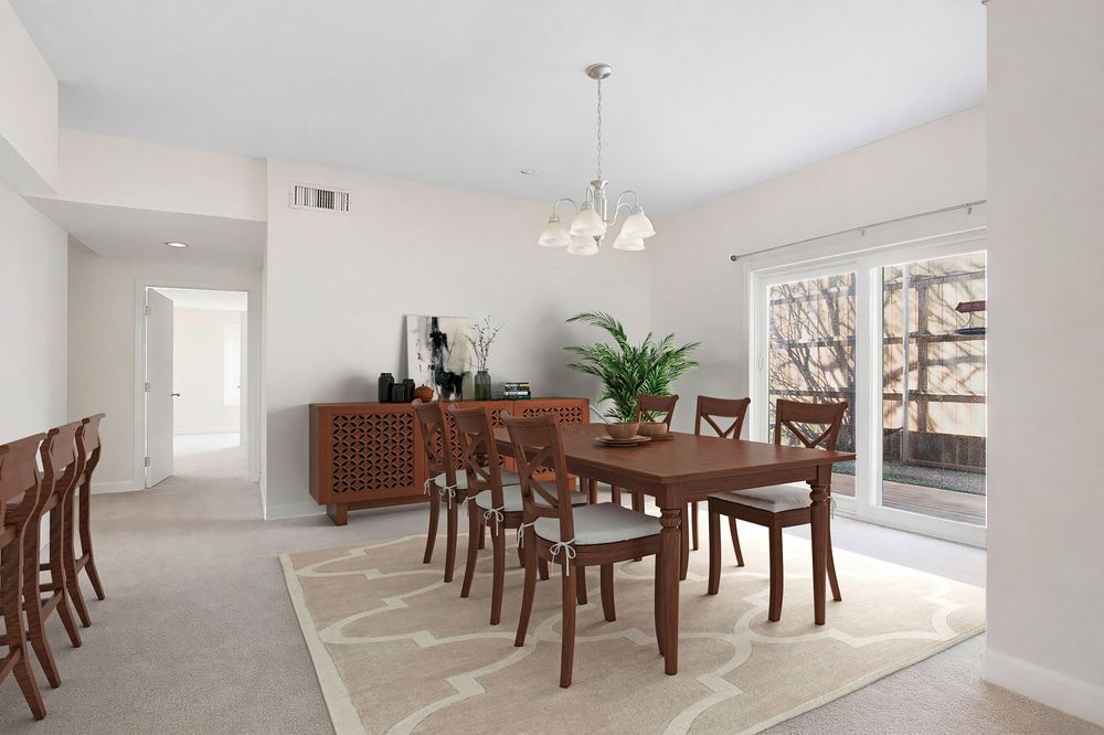 Elegant dining room with dark wood table and chairs, chandelier, patterned rug, sideboard, and sliding glass doors to balcony.