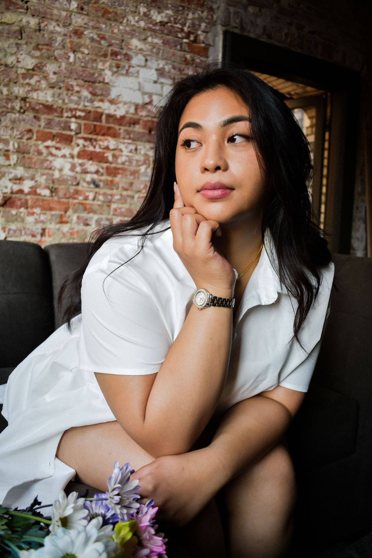 Portrait photo against brick wall featuring white button down shirt and floral arrangement in casual indoor setting. Seattle photography