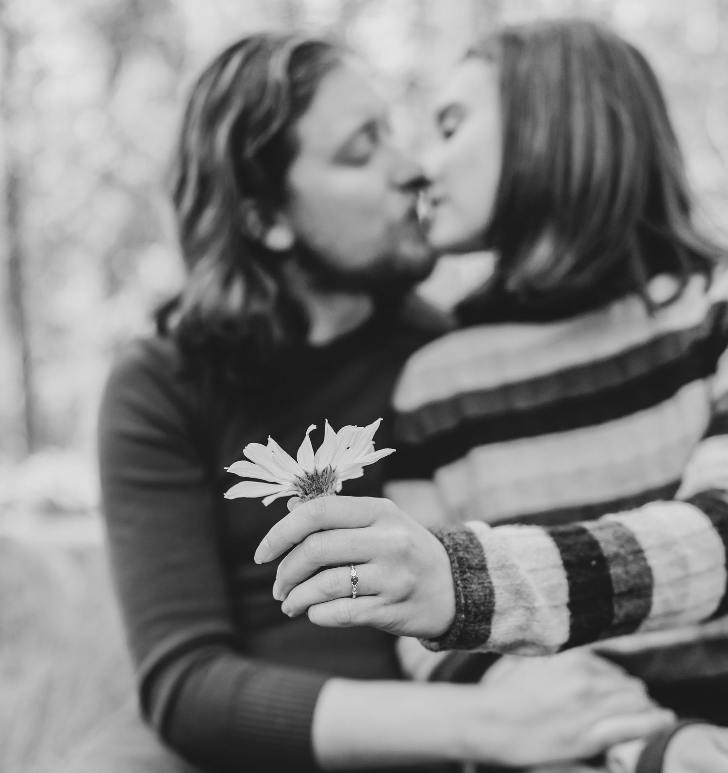 Black and white romantic portrait with a daisy flower in soft focus.