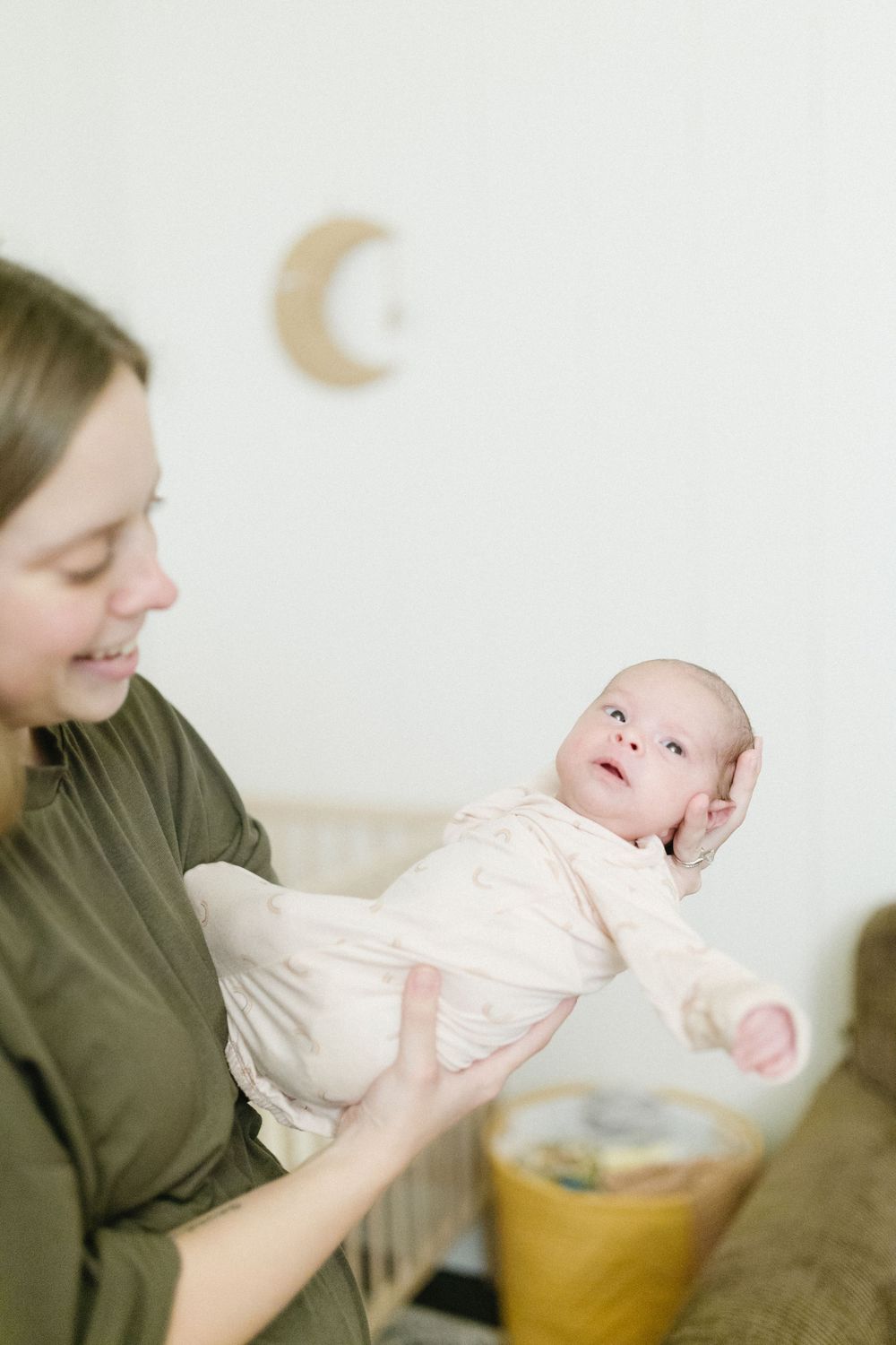 Tender moment between mother and baby beneath decorative moon wall art.