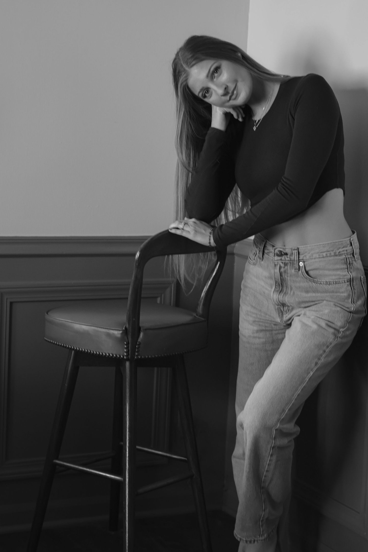 Artistic black and white portrait series showing casual poses against a dark wall.