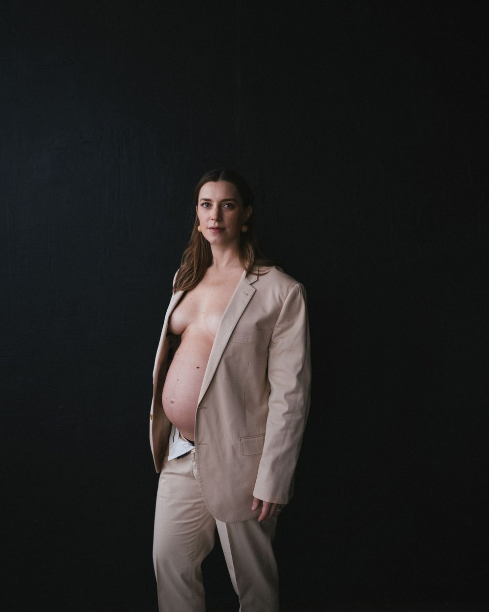 A maternity portrait in neutral tones featuring professional business attire.