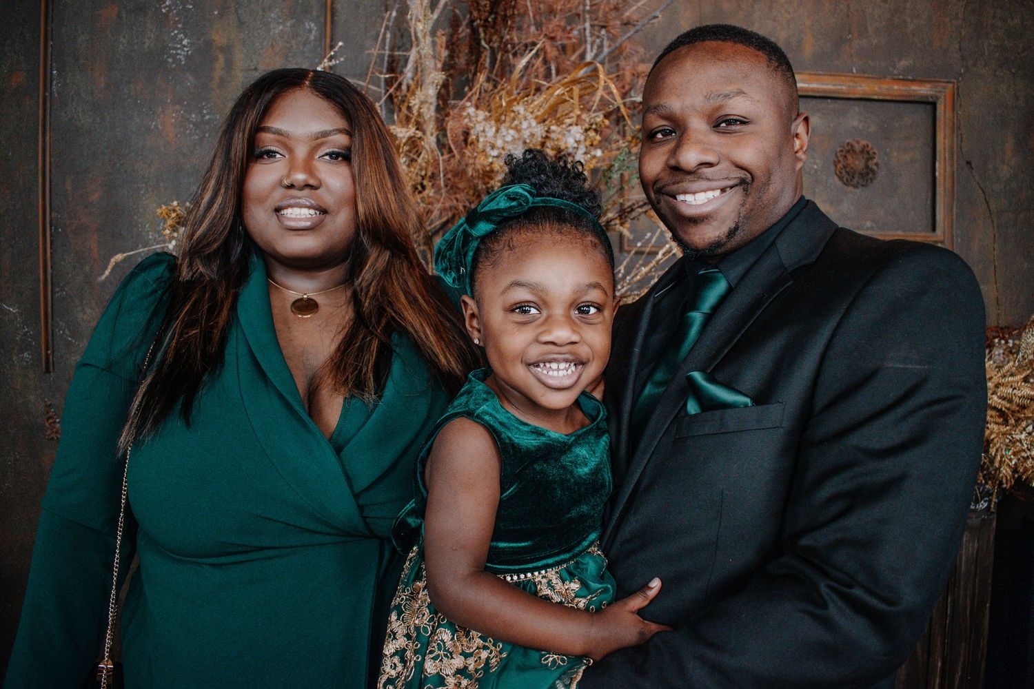 Tacoma family photo A family wearing coordinated emerald green outfits poses together against a dark textured backdrop for a formal portrait
