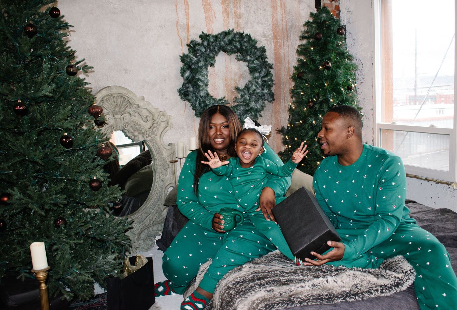Tacoma family photography. A family wearing matching green polka dot pajamas sit together on a couch by a Christmas tree and wreath.