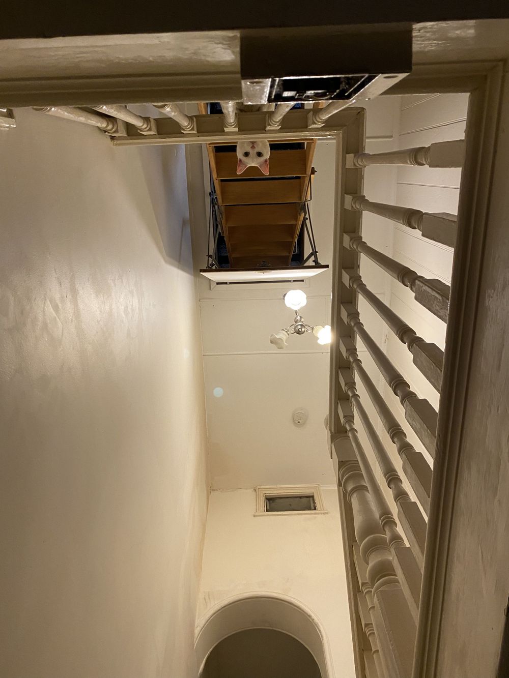 View looking up a white stairwell with wooden steps and white railings.
