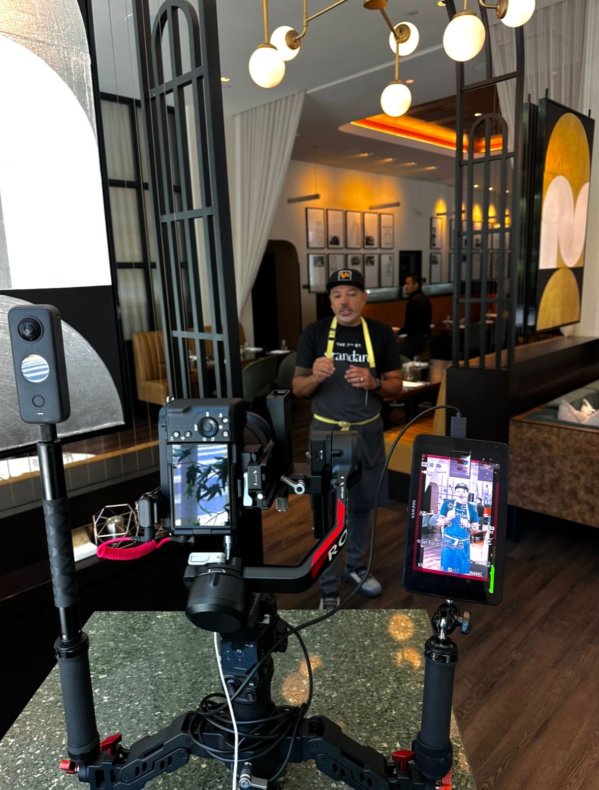 Streaming setup with multiple monitors and camera equipment mounted in a restaurant or cafe interior.