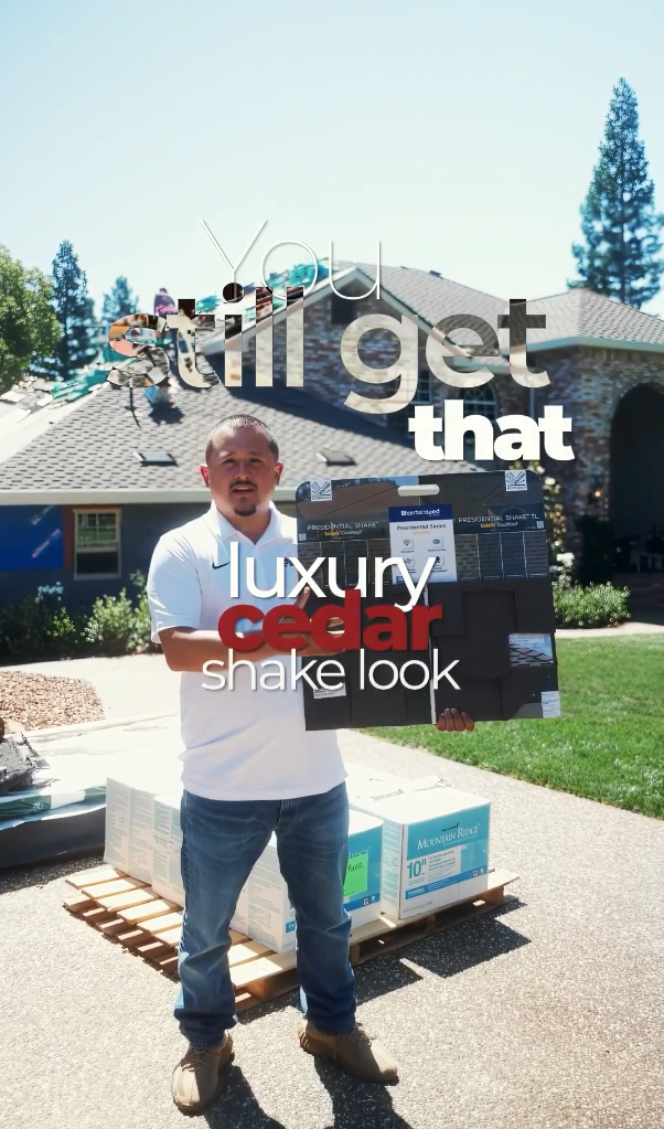 Man stands proudly in driveway with luxury cedar shake roofing materials, showcasing new roof installation on suburban home.
