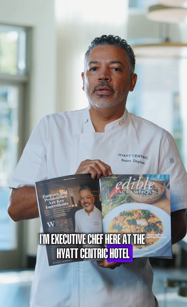 Executive Chef Pedro Depina in white uniform holds Edible Sacramento magazine at Hyatt Centric Hotel.