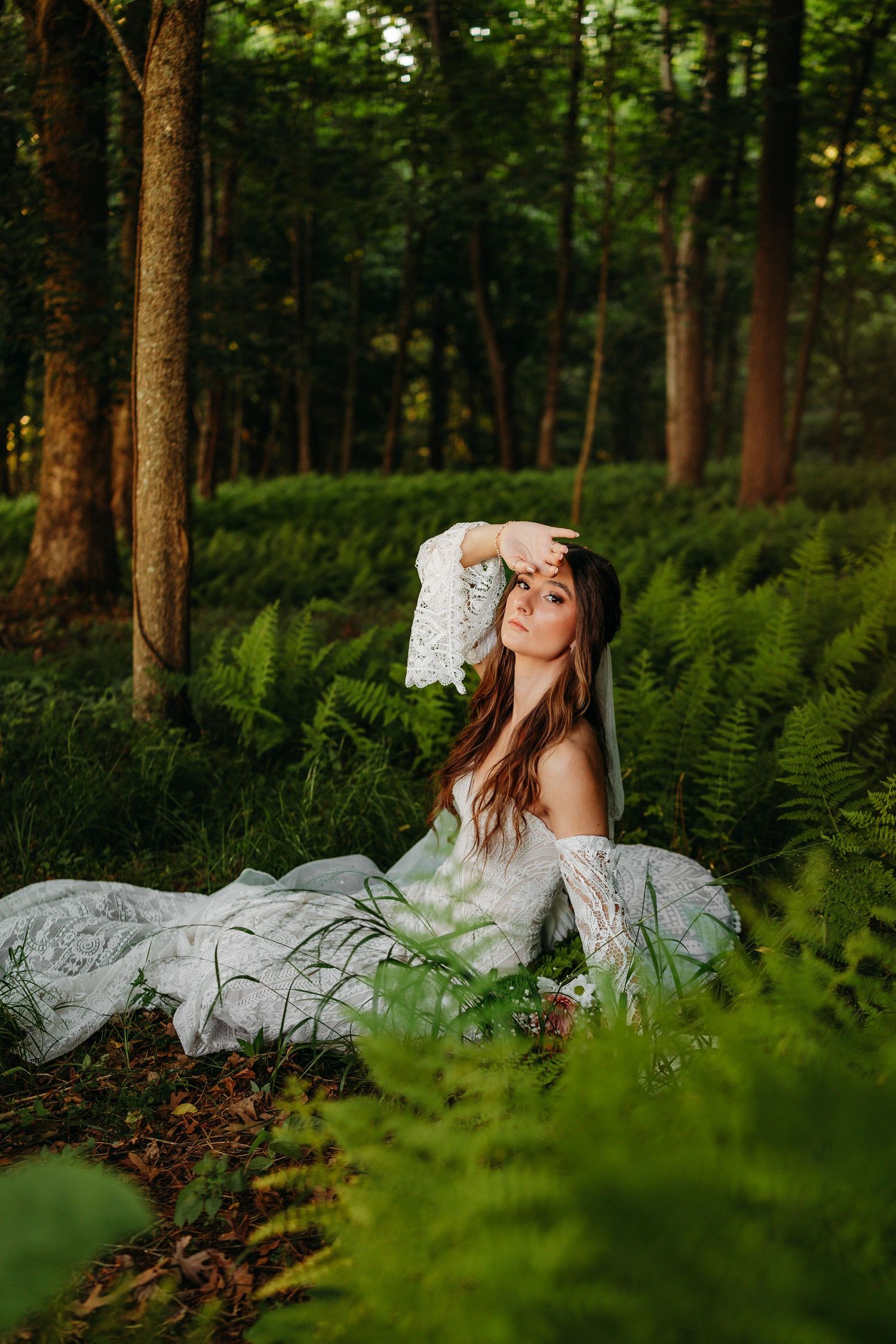Young woman in green top and white skirt standing among colorful blooming flowers in a garden.