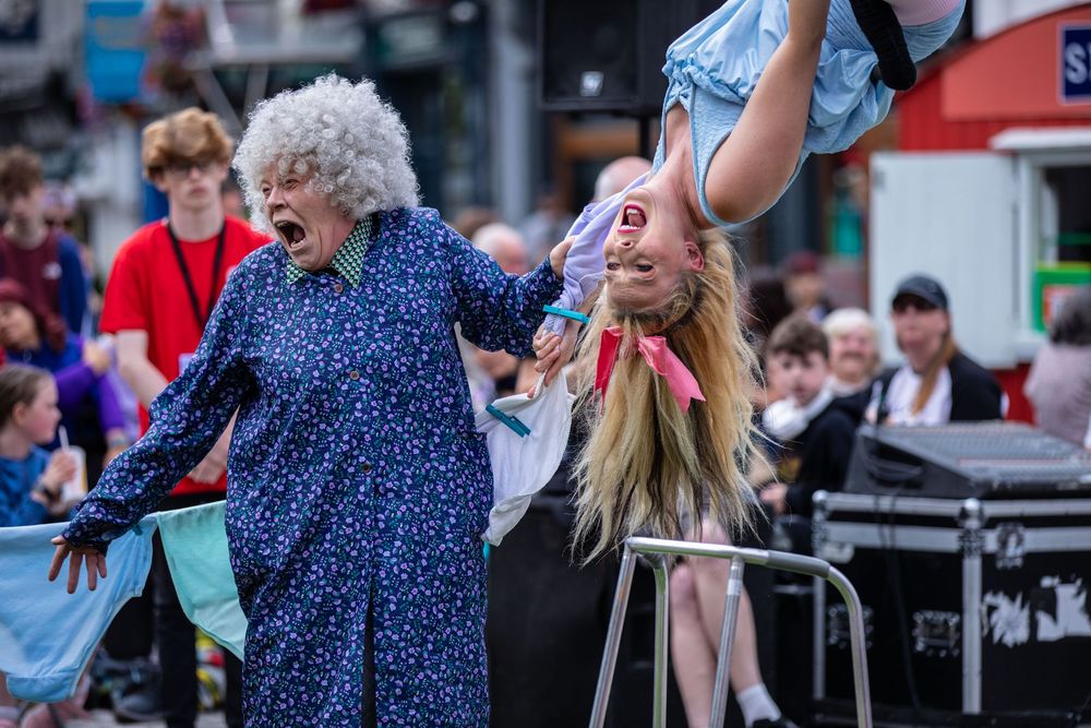 People in blue outfits dance and perform at an outdoor street festival or celebration.