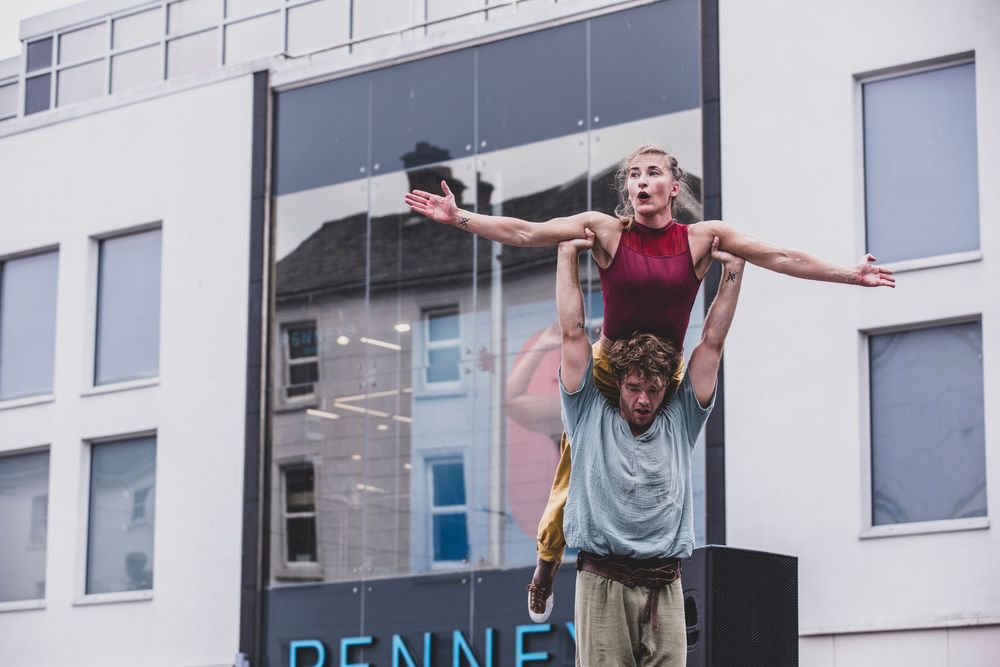 People performing synchronized dance moves on apartment balconies during social distancing in an urban setting.