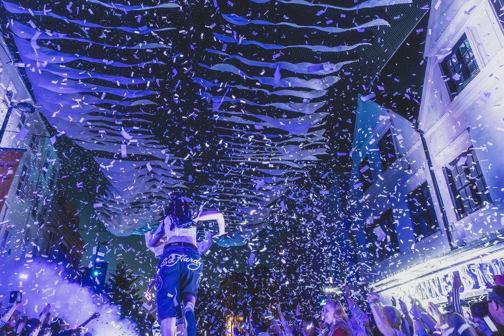 A performer on stage surrounded by confetti and blue lighting during a concert performance.