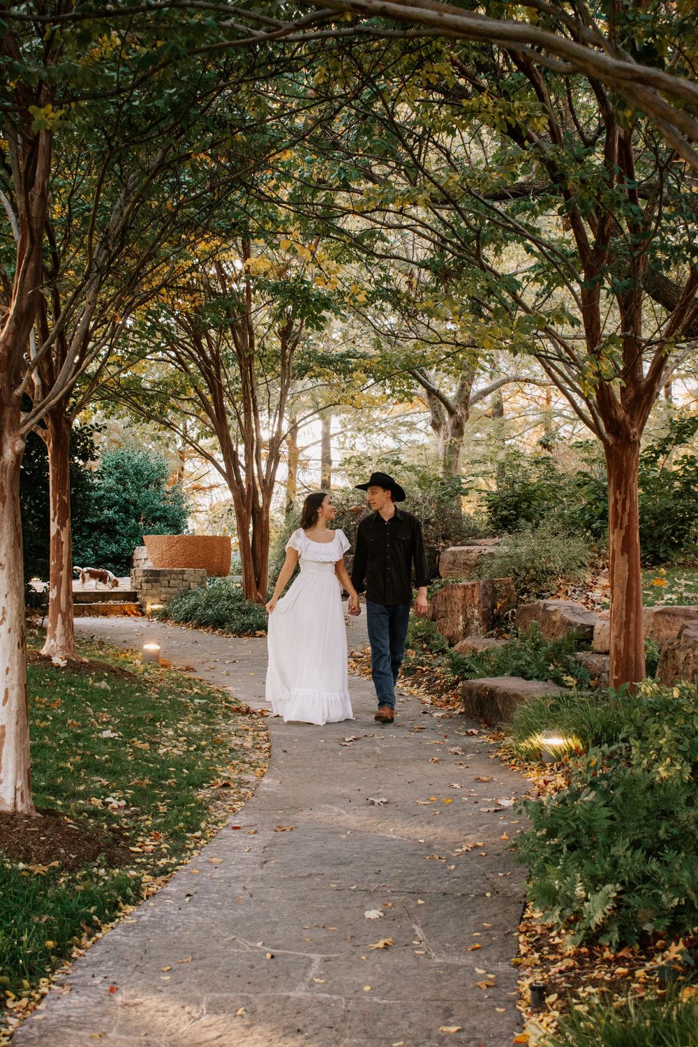 couple walkind down tree lined path at Myriad Botanical Gardens in Oklahoma City, Oklahoma