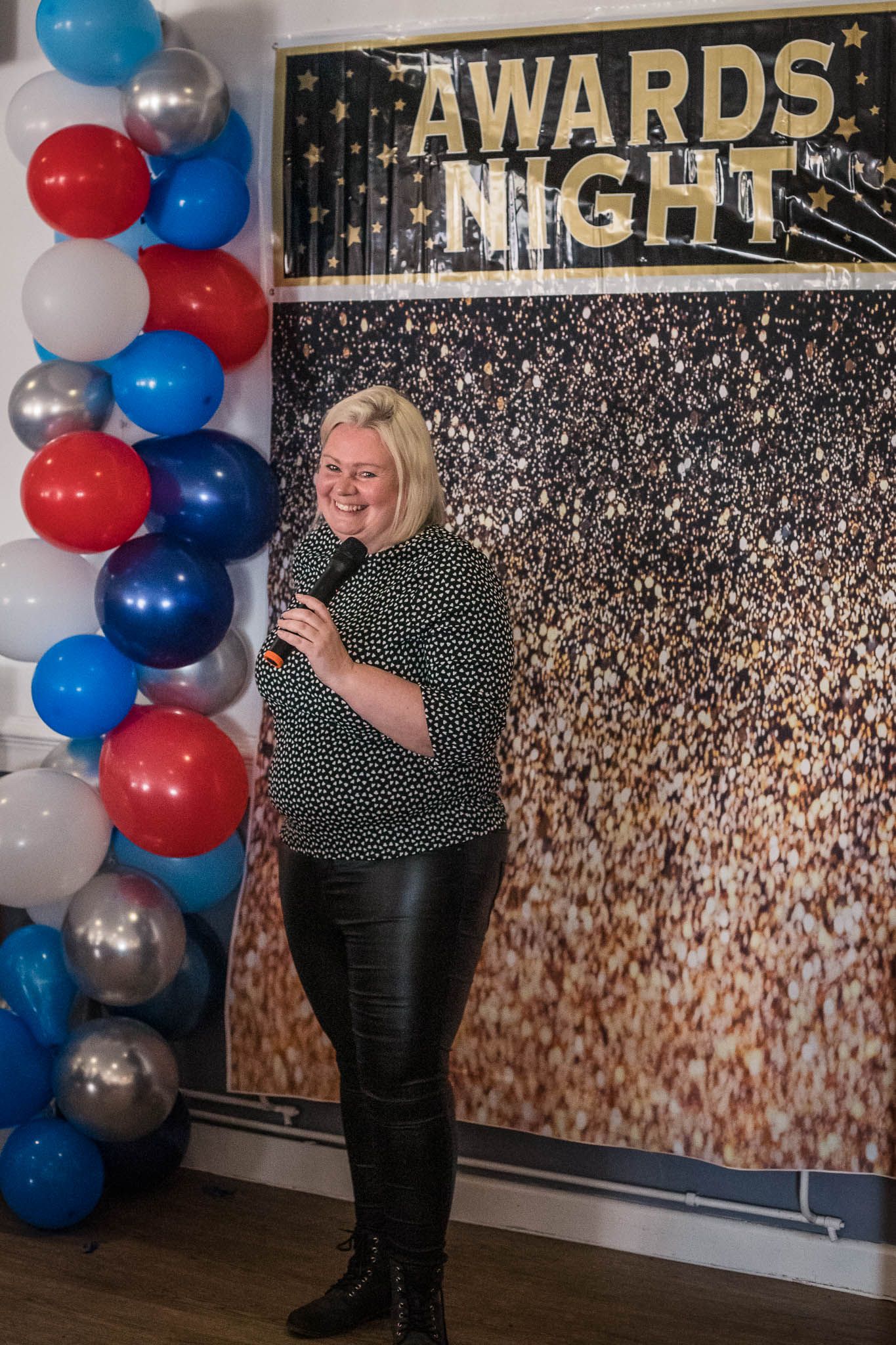 Blonde woman holding a microphone hosting a Sports Awards Night for Junior Hockey players at Redditch Hockey Club.