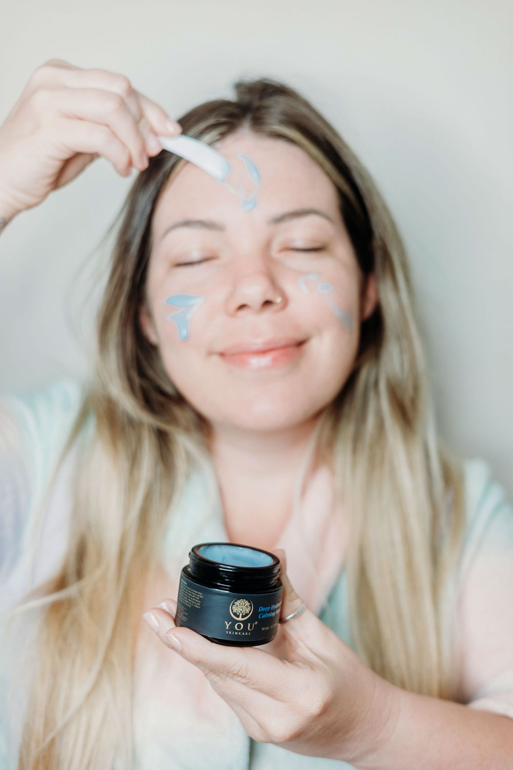 A woman putting a face mask on with a smile.