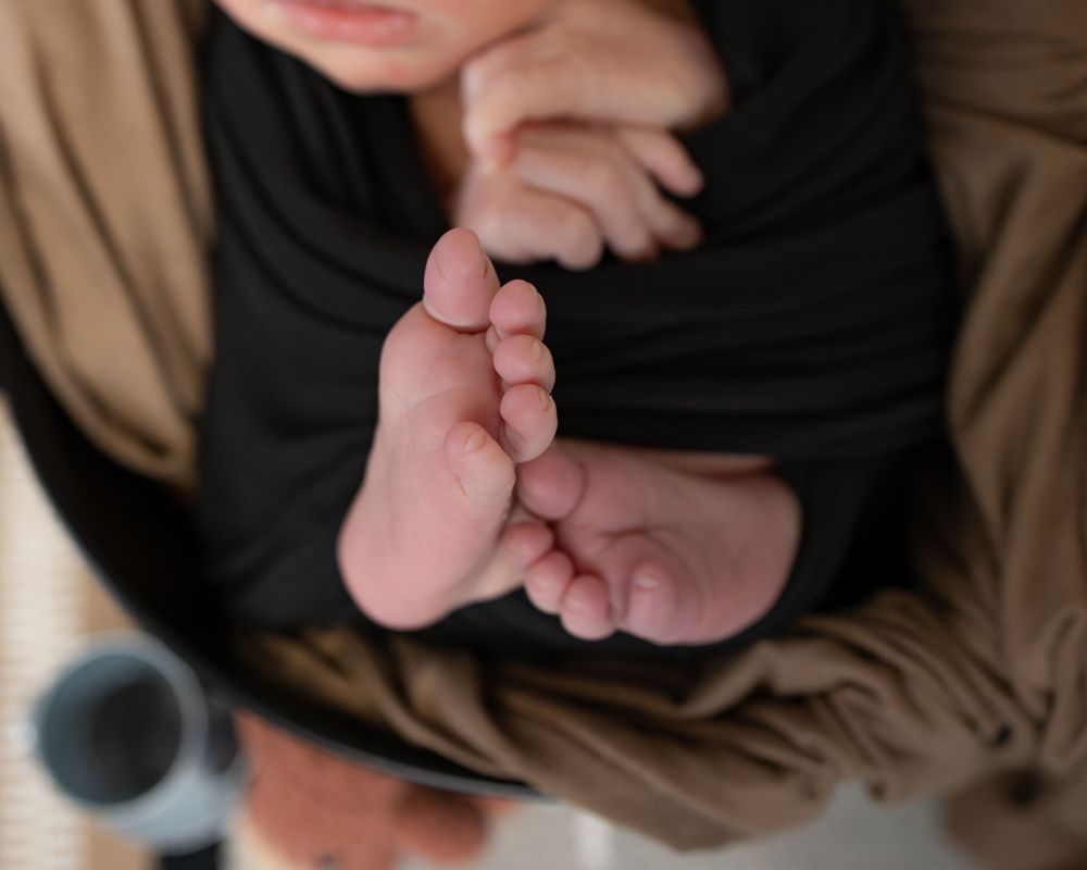 A close-up view of tiny baby feet resting on brown fabric.