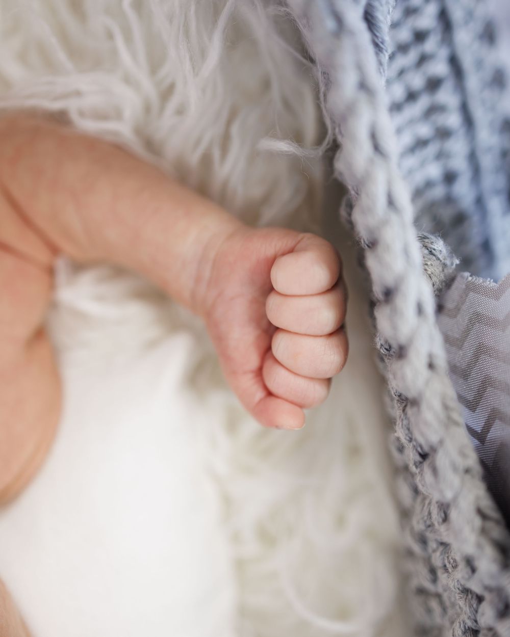 Close up view of a tiny baby foot against soft white and gray knitted blankets.
