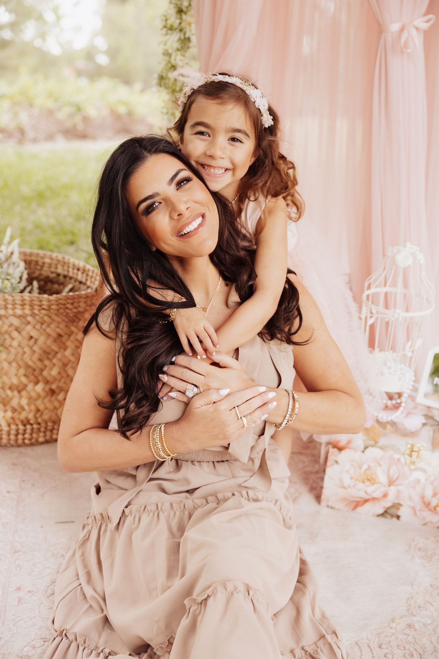 A heartwarming outdoor portrait of a parent and child cuddling and smiling together against a pink backdrop.