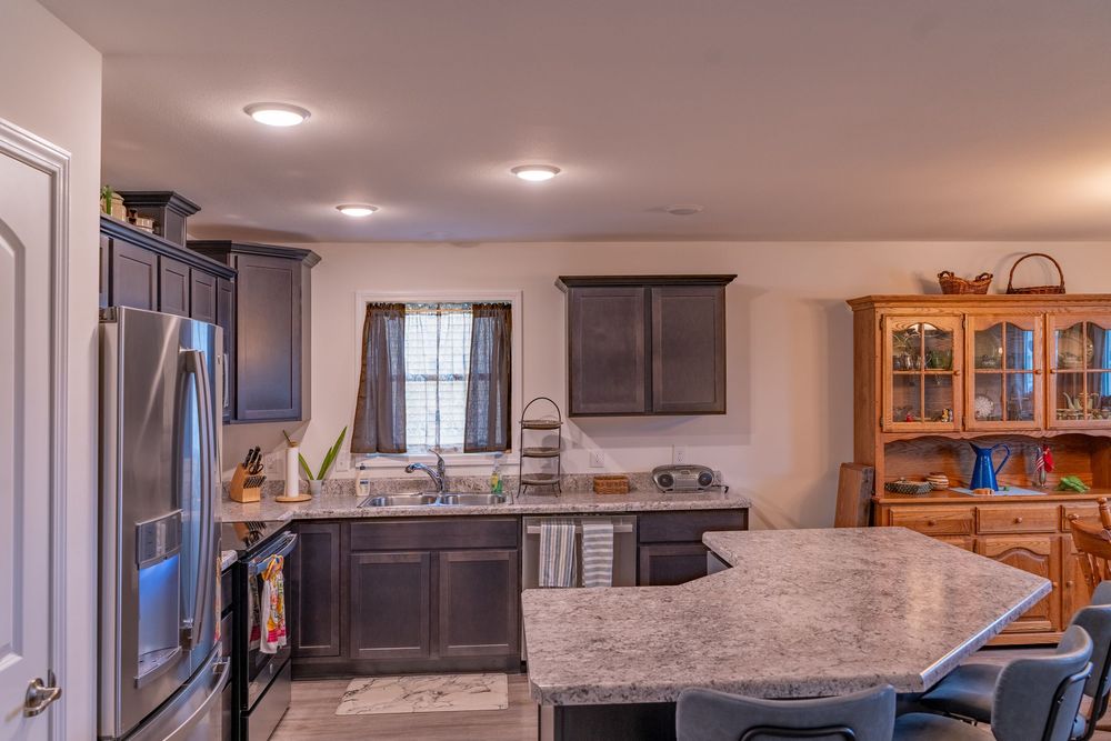Modern kitchen with dark cabinets, granite countertops, stainless steel appliances and an oak china cabinet.