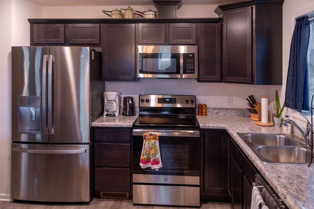 Modern kitchen featuring dark brown cabinets, stainless steel appliances, and grey granite countertops in an L-shaped layout.