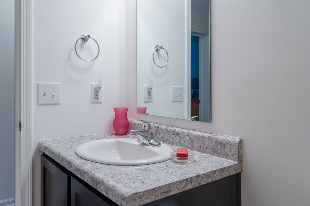 Single bathroom vanity with gray granite countertop, white sink, and circular towel rings mounted on wall.