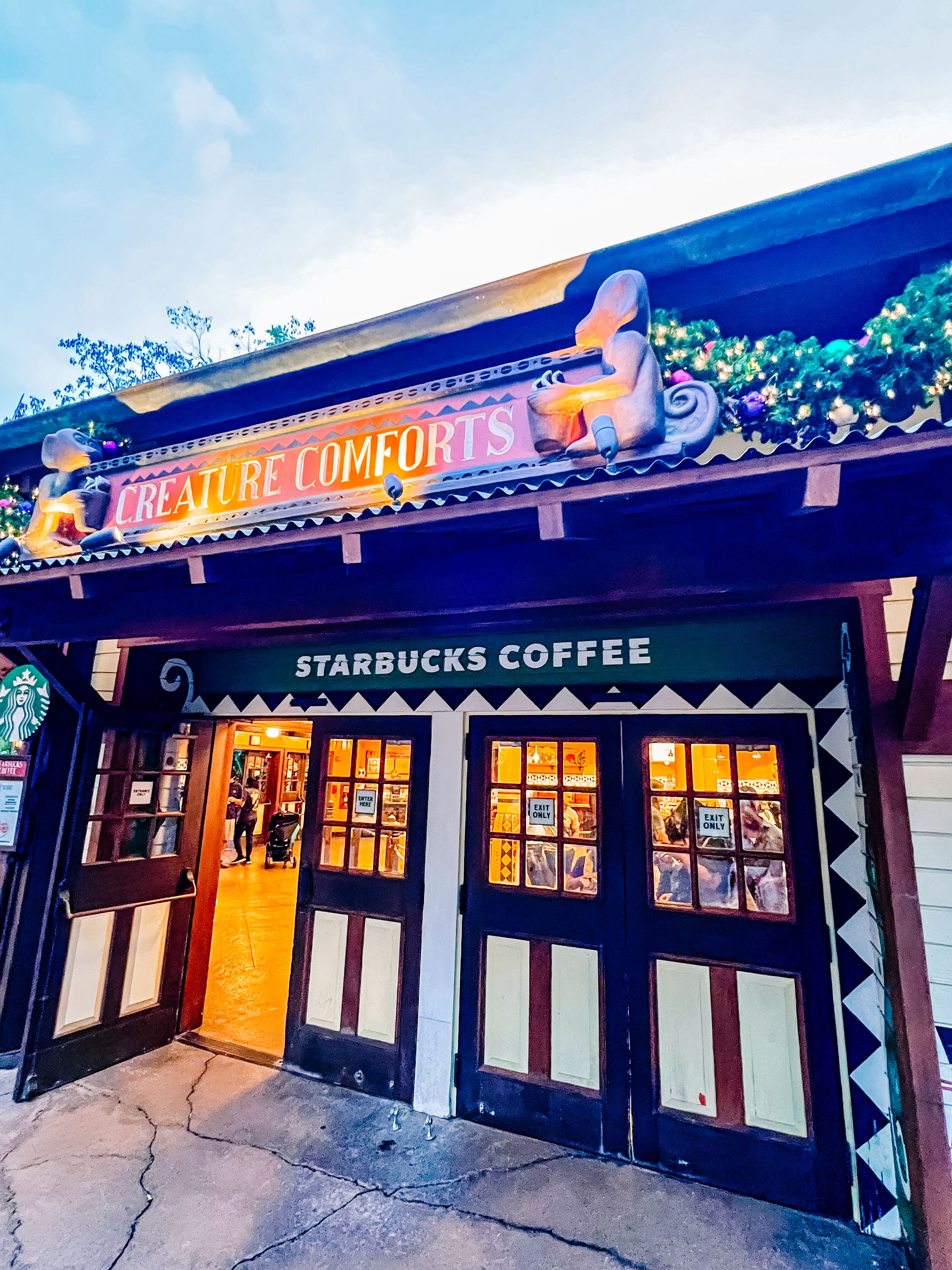 A Starbucks Coffee storefront with a 'You'll Be Comforted' sign lit up at night.