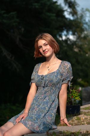 A senior girl sitting on a ledge in the sun