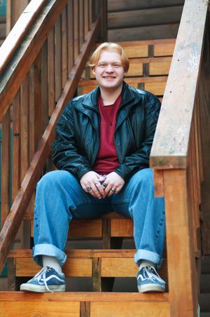 A portrait of a senior boy sitting on a staircase outdoors.
