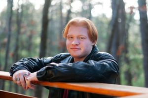 A portrait of a senior boy leaning against a railing