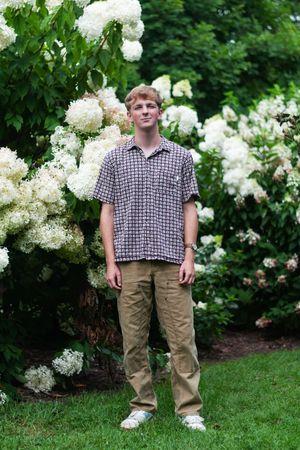 A portrait of a senior boy with white and green flowers in the background