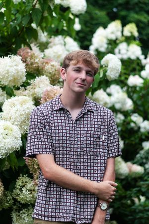 A portrait of a senior boy with white and green flowers in the background