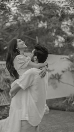 Black and white sequence of couple embracing and spinning in casual white outfits outdoors.