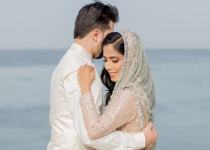 Romantic beachside wedding portraits with lace veil against misty ocean background.