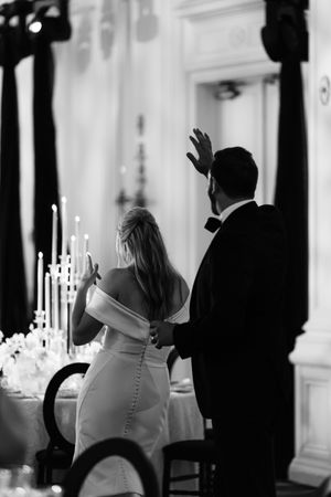 Wedding reception silhouettes with candlelit tables in an elegant white interior.