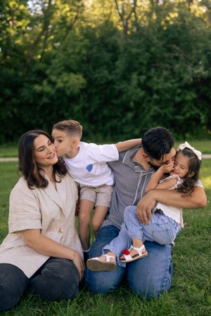 Family shares intimate moments while sitting together on grass during sunset during a family photoshoot