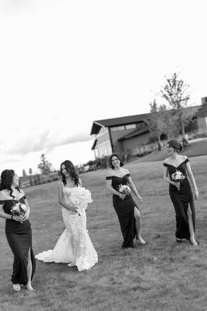 Wedding party poses playfully on a grassy hill in black and white photography.