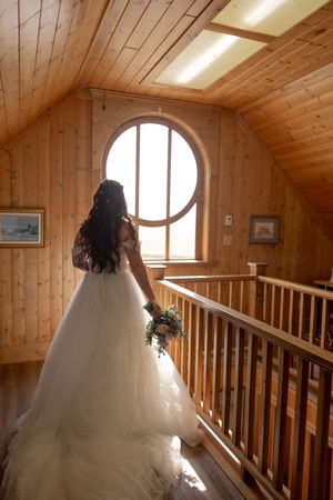 Wedding dress flowing through wooden attic space with round window and natural light.