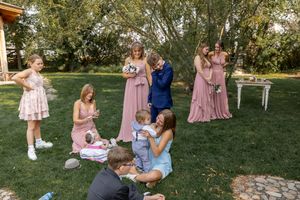 Outdoor garden wedding reception with pink-dressed guests and vintage decor.