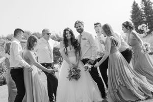 Wedding party mingles and laughs together during outdoor celebration.
