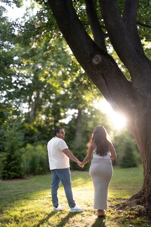 Couple walks hand in hand through Jack Darling park during golden hour maternity shoot.