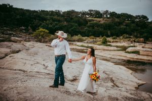 Elopement couple at the river in Hill Country, Texas as he tips his cowboy hate at his bride.