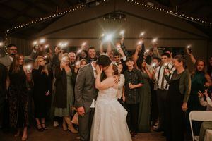 Bride and Groom kissing in front of their guests  who are holding flash lights behind them at a venue in Clarksville, TN.