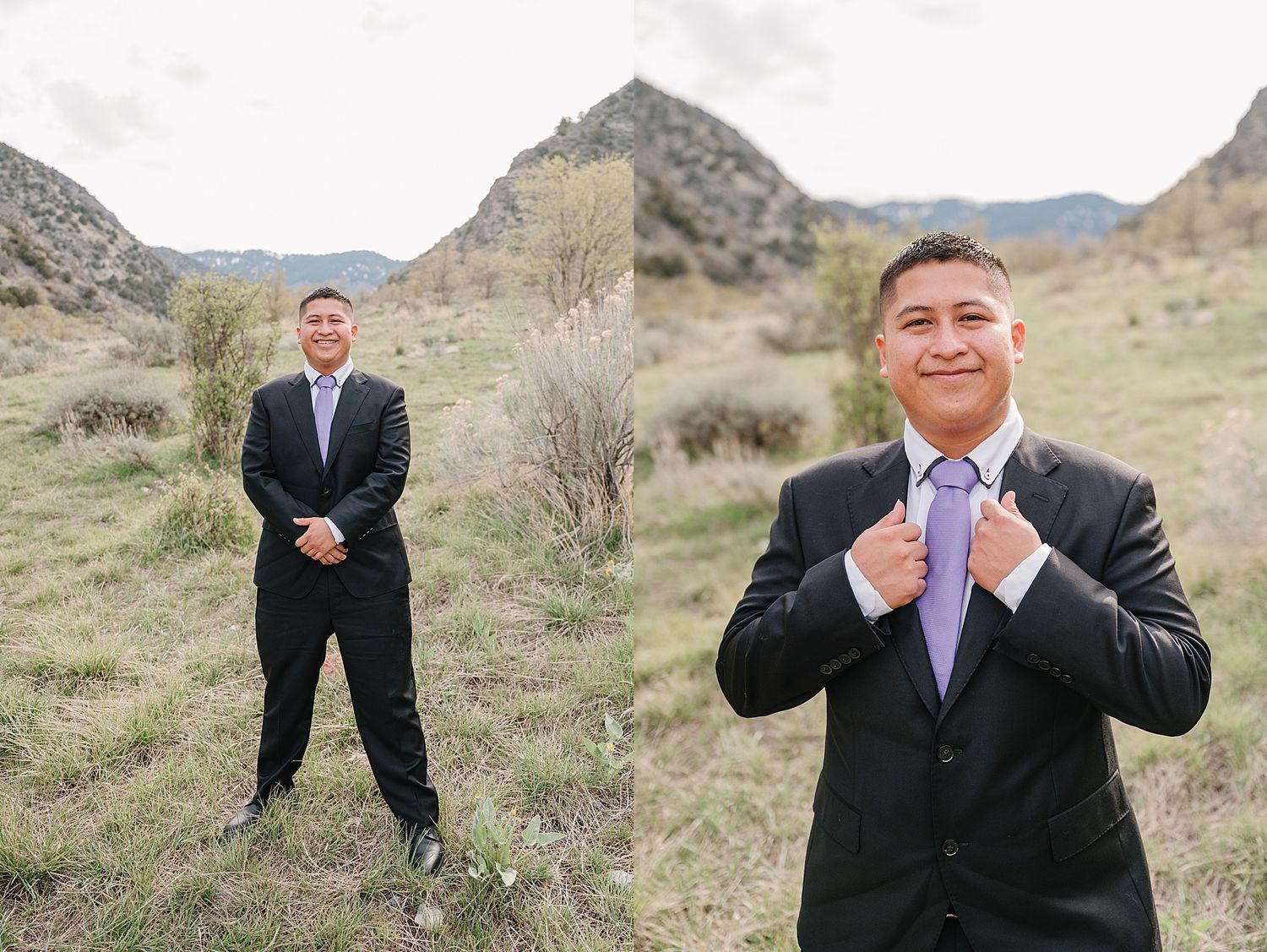 Two people in formal black suits and ties pose on a grassy hillside with mountains in the background.