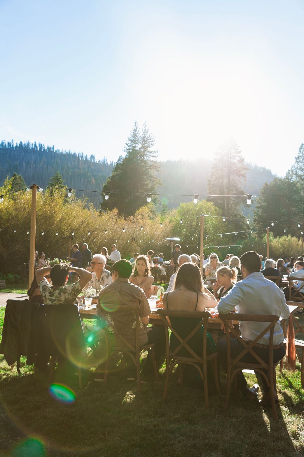 A sunset wedding reception with string lights and mountain views in the background.