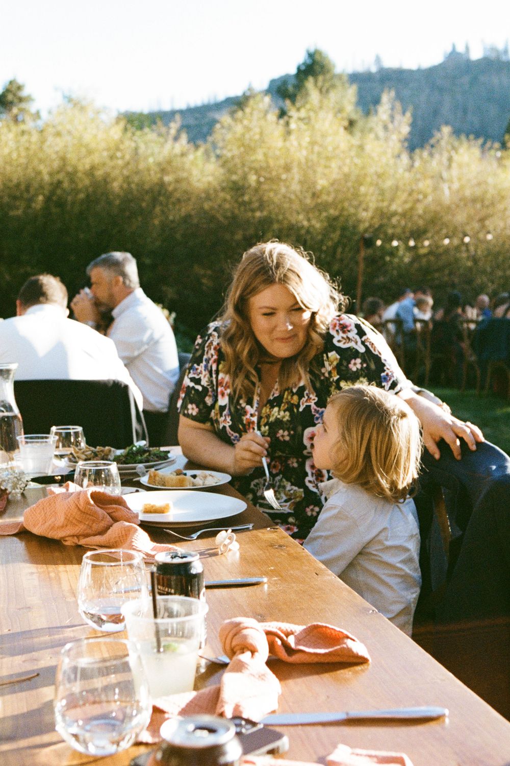 Wedding guests enjoying dinner at rustic outdoor tables.